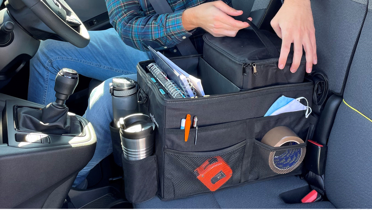A tidy campervan front seat featuring the myXplorer van organiser, with its multiple compartments holding drinks, a tablet, and other travel essentials securely in place.